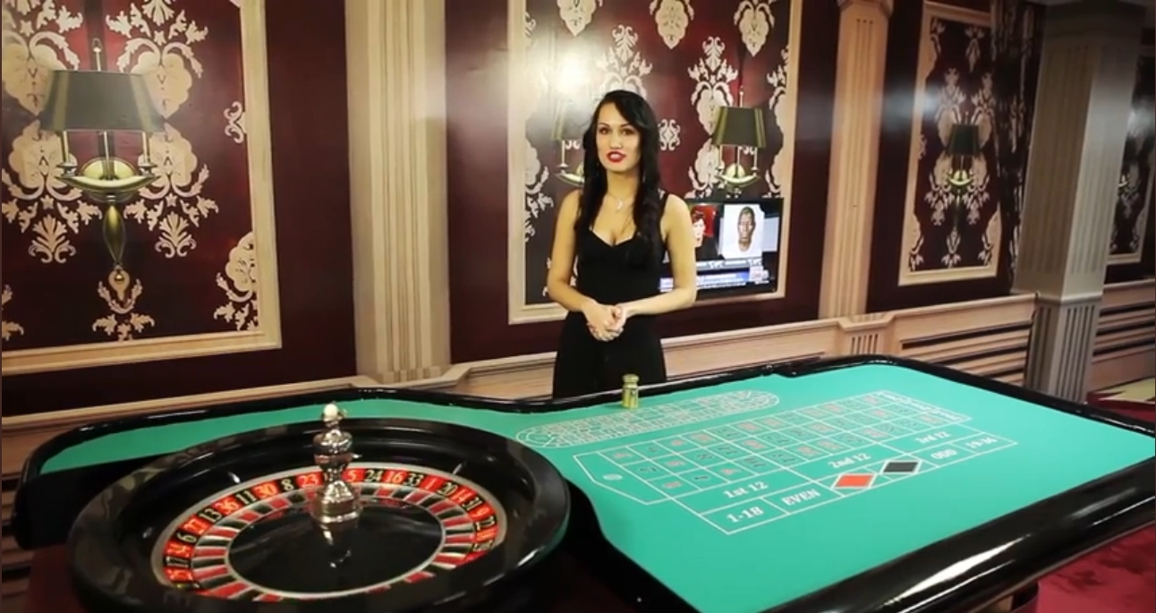 Девушка крупье около размеченного стола с колесом рулетки