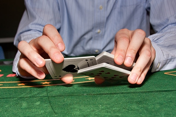 Руки дилера, тасующего карты за игорным столом